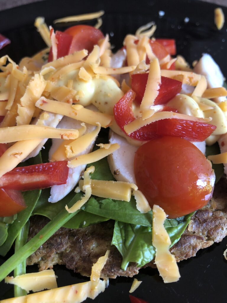 Glutenfri blomkålsbrød toppet med kylling, karry dressing, spinat, tomat, peberfrug og chili gouda.